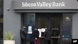 People read signs posted outside of an entrance to Silicon Valley Bank in Santa Clara, California, March 10, 2023.