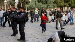Anggota pasukan keamanan Israel berjaga di dekat sejumlah warga Palestina yang tengah berdoa di kompleks Masjid Al-Aqsa di Yerusalem, pada 9 April 2023. (Foto: Reuters/Ammar Awad)