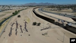 Migrants wait for U.S. authorities between a barbed-wire barrier and the border fence at the US-Mexico border, as seen from Ciudad Juarez, Mexico, May 9, 2023. 