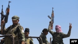 Fighters of the Syrian Democratic Forces (SDF) gesture as they move to the Dhiban front line in eastern Syria's Deir el-Zour province, Sept. 4, 2023, during a guided media tour organized by the SDF.