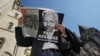 Seorang demonstran memegang koran yang menampilkan wajah Julian Assange dalam aksi protes di luar Pengadilan Tinggi London pada 20 Mei 2024. (Foto: AP/Kin Cheung)