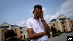 Mohamed, a 19-year-old fleeing political persecution in Mauritania, poses for a photo that obscures his face to protect his identity, outside the Crossroads Hotel, before heading into town for a work opportunity, May 22, 2023, in Newburgh, N.Y. 