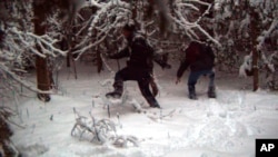 FILE - In this surveillance image provided by the United States Border Patrol Swanton sector, two individuals illegally cross the U.S./Canada border during January 2023 in the Vermont, New Hampshire and New York enforcement sector. 