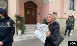 Gulmira Aslanova, whose husband, journalist Polad Aslanov, is serving 13 years in prison, holds a sign saying, "Don’t torture. Free," during a protest she held in front of the presidential administration building in Baku, Azerbaijan, April 8, 2022. (VOA)