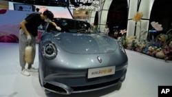 FILE - A worker wipes an Ora, a Chinese electric car, during the Auto Shanghai 2023 show at a convention center in Shanghai, April 18, 2023. The Biden administration will be increasing tariffs on certain imports from China, including EVs.