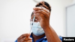 FILE - A nurse prepares a dose of COVID-19 vaccine at the University Hospital Coventry, in Coventry, England, April 22, 2022.