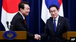 FILE - South Korean President Yoon Suk Yeol, left, and Japanese Prime Minister Fumio Kishida shake hands following a joint news conference Tokyo, March 16, 2023.