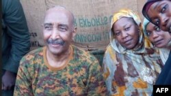 A handout image posted on the Sudanese Armed Forces' Facebook page shows army chief General Abdel Fattah al-Burhan posing for a picture with civilians in Khartoum during a tour of a neighborhood in the capital on Aug. 24, 2023. 