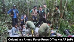 In this photo released by Colombia's Armed Forces Press Office, soldiers and Indigenous men tend to the four Indigenous children who were missing after a deadly plane crash, in the Solano jungle, Caqueta state, Colombia, June 9, 2023.