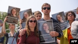 Relatives, friends and supporters hold portraits of French teacher Cecile Kohler, detained along with her partner Jacques Paris in Iran, during a rally in their support in Paris, May 14, 2023. 