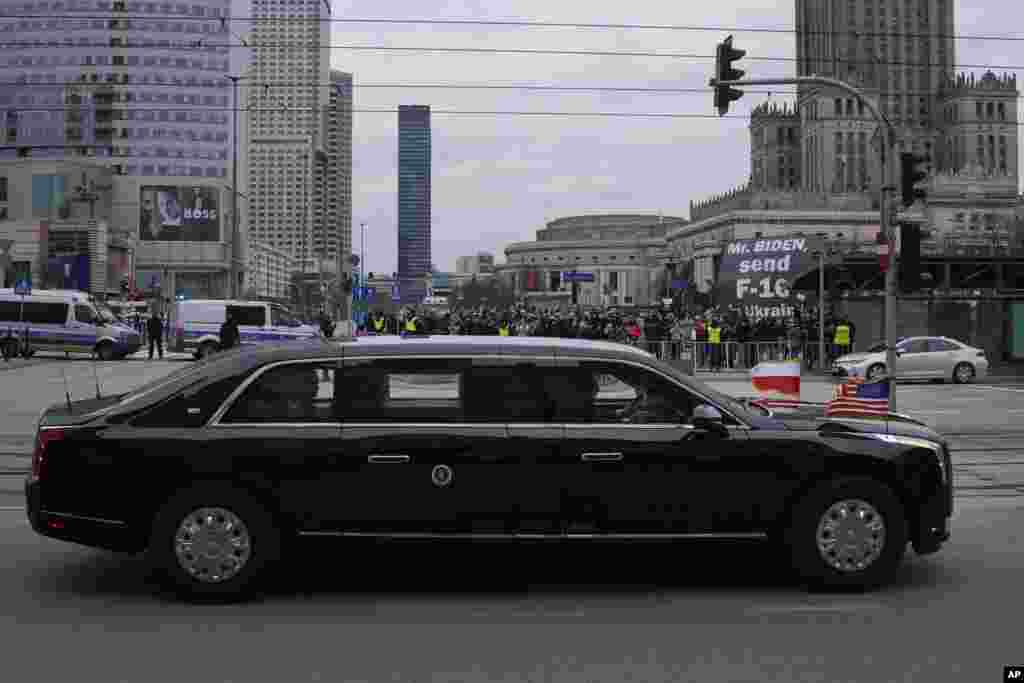 Protesters, rear, hold a sign asking U.S. President Joe Biden to send fighter jets to Ukraine as he leaves his hotel for the Polish Presidential Palace for a meeting with the B9 leaders in Warsaw, Poland.
