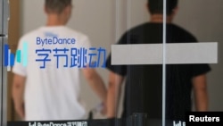 FILE - People walk past a logo of Bytedance, the China-based company which owns the short video app TikTok, or Douyin, at its office in Beijing, July 7, 2020.