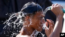 A man douses himself with water along a street as hot temperatures continue in Manila, Philippines, April 26, 2024.