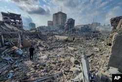 Palestinians walk through the rubble of buildings destroyed by Israeli airstrikes in Gaza City, Oct. 10, 2023.