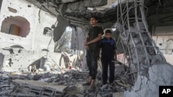 রাফায় রাতভর ইসরায়েলি হামলার পর ফিলিস্তিনিরা একটি বাড়ির ধ্বংসস্তূপে দাঁড়িয়ে আছে। ৩ মে, ২০২৪।