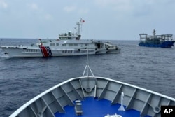 FILE - Sebuah kapal penjaga pantai China (kiri), dengan kapal milisi China (kanan), menghalangi kapal penjaga pantai Filipina, BRP Sindangan ketika mencoba menuju Second Thomas Shoal di Laut Cina Selatan, 4 Oktober 2023. (AP/Joeal Calupitan)