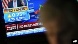Traders work on the floor of the New York Stock Exchange in New York, on March 22, 2023. News on the Federal Reserve interest rate hike appears on a monitor in the background.
