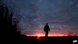FILE - In this Nov. 20, 2015, photo, a man walks along a trail during sunset near Manhattan, Kan. 