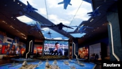 资料照片：北京的中国军事博物馆内在中国领导人习近平的巨幅电子屏幕前展示的军事装备模型。（2022年10月8日）