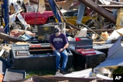 An employee of a body shop collects tools from near damage the morning after a tornado rolled through, May 26, 2024, in Valley View, Texas.