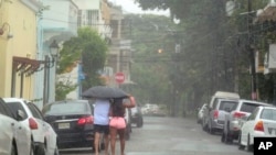 People walk in the rain brought by Tropical Storm Franklin in Santo Domingo, Dominican Republic, Aug. 23, 2023.