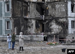 People pay their respects in front of a damaged multistory residential building, where a Russian strike killed 23 people, in Uman, in Ukraine's Cherkasy region, April 30, 2023.