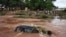 Des personnes regardent un 4x4 submergé par les eaux de crue à Bamako en 2013. 