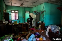 A soldier from the Karen National Liberation Army (KNLA) inspects the house of a high-ranked Myanmar soldier, at a military base at Thing Naga Nyi Naung village on the outskirts of Myawaddy, April 15, 2024.