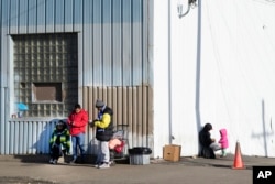FILE - Immigrants stand outside a shelter in the Pilsen neighborhood of Chicago, Dec. 19, 2023.