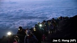 แฟ้มภาพ - ภาพนักปีนเขากำลังเดินขึ้นยอดภูเขาไฟฟูจิ ประเทศญี่ปุ่น ก่อนพระอาทิตย์ขึ้น เมื่อ 27 ส.ค. 2562 