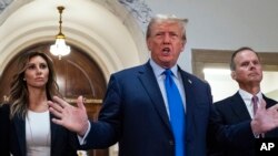 Former President Donald Trump speaks with journalists before entering a courtroom in New York, Oct. 2, 2023, to attend the start of a civil trial in a lawsuit that already has resulted in a judge ruling that he committed fraud in his business dealings.