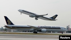 FILE: Pesawat Airbus A330-300 Singapore Airlines lepas landas, saat Boeing 787-10 Dreamliner melintas di landasan pacu Bandara Changi, Singapura, 28 Maret 2018. (REUTERS/Edgar Su)