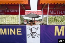 A police officer stands in front of a pile of seized illegal drugs before a destruction ceremony in Yangon, June 26, 2023.