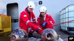 This photo released by Israel's Antiques Authority on June 20, 2024, shows Jacob Sharvit, left, and Dr. Karnit Bahartan with ancient jars that were carried on the world's oldest known deep-sea ship.