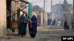 করাচির এক এলাকায় দু'জন আফগান নারী বাচ্চা নিয়ে হাঁটছেন। ফটোঃ ২৬ জানুয়ারি, ২০২৪।