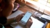 FILE - A woman uses her mobile phone to check Facebook in Naypyidaw, March 16, 2021, as Myanmar authorities ordered telecommunication companies to restrict their services on the mobile data networks, following the February 1 military coup.