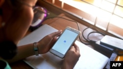 FILE - A woman uses her mobile phone to check Facebook in Naypyidaw, March 16, 2021, as Myanmar authorities ordered telecommunication companies to restrict their services on the mobile data networks, following the February 1 military coup.