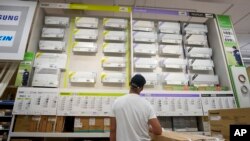 FILE - A man looks at a a wall displaying air conditioning models on sale at department store, in Rome, July 25, 2023.