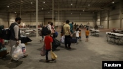 FILE - Special Immigrant Visa holders from Afghanistan walk through the in-processing building after their evacuation at Camp As Sayliyah, Qatar, Aug. 20, 2021. (U.S. Army/Sgt. Jimmie Baker/Handout via Reuters)