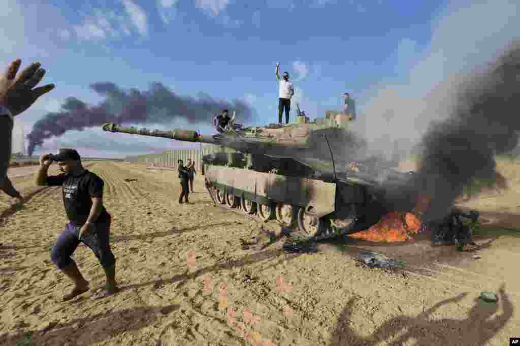 Palestinians celebrate at a destroyed Israeli tank at the Gaza Strip fence east of Khan Younis, Israel, on Oct. 7, 2023.