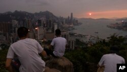 FILE - Mainland Chinese tourists look at sunset from a hill in Hong Kong, April 26, 2023.