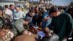 FILE - Supporters of Shiite cleric Muqtada al-Sadr sign a pledge to stand against LGBTQ rights, outside a mosque in Kufa, Iraq, Dec. 2, 2022.