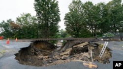 FILE - Train tracks on the Fitchburg Line extend over an area washed out by recent flooding, Sept. 13, 2023, in Leominster, Mass. 