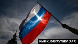 Seorang pria mengibarkan bendera nasional Rusia di pusat kota Moskow menjelang Hari Rusia pada 11 Juni 2023. (Foto: AFP/Kirill KUDRYAVTSEV)
