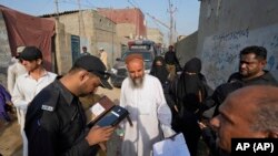 করাচির এক পাড়ায় অবৈধ অভিবাসী খুঁজতে পুলিশ স্থানীয় বাসিন্দাদের পরিচয়পত্র পরীক্ষা করছেন। ফটোঃ ৩ নভেম্বর, ২০২৩।