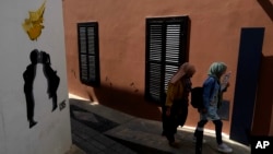 FILE - Migrants walk inside the medieval core at the old city of the divided capital Nicosia, Cyprus, May 10, 2023. 