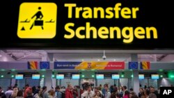 Passengers arriving at Henri Coanda International Airport pass under a Schengen zone transfer sign, in Otopeni, near Bucharest, Romania, March 31, 2024. 