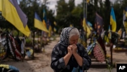 Svitlana Sushko, 62, sobs while visiting the grave of her youngest son, a Ukrainian soldier killed last year in the war against Russia, in Kyiv, Ukraine, Aug. 3, 2023. 