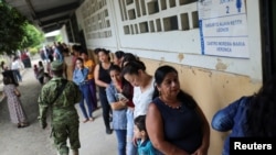 People queue to vote at a polling station during the presidential election, in Canuto, Ecuador, Oct. 15, 2023. 