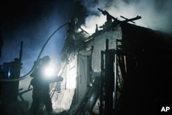 Rescue workers extinguish a fire at a house damaged in a Russian drone strike on residential neighborhood in Kharkiv, Ukraine, April 4, 2024.